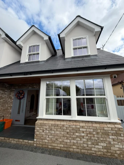 White sash windows align across the front bay and the two dormer openings.
