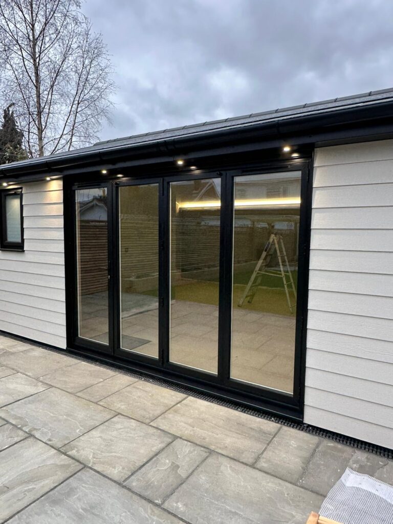 Home Dark-framed glazed doors in a garden room with light-coloured cladding