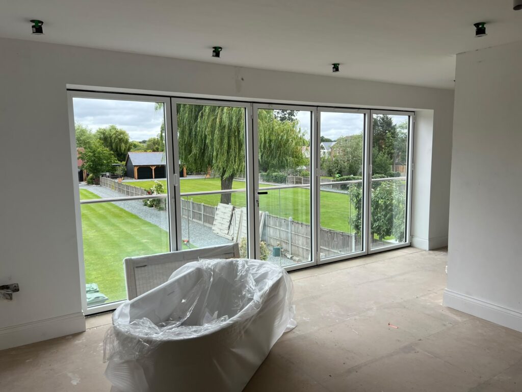 Home Wide glazed doors opening from an unfinished room onto a garden